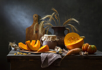 A still life with pumpkin and vegetables against a dark background. Pumpkin cream soup is being prepared