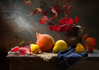 Still life with a pumpkin and a bouquet of wild grapes on a dark background