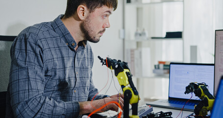 Closeup young adult male freelance developer typing write prompt AI bot app program nomad terminal with coding at office. Artificial intelligence dashboard, robotics, user interface, machine learning.