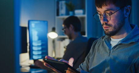 Team adult male freelance developer work late use tablet write prompt AI bot app program nomad...