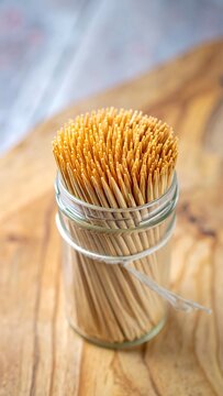 Close-up of a jar filled with wooden toothpicks on a wooden board