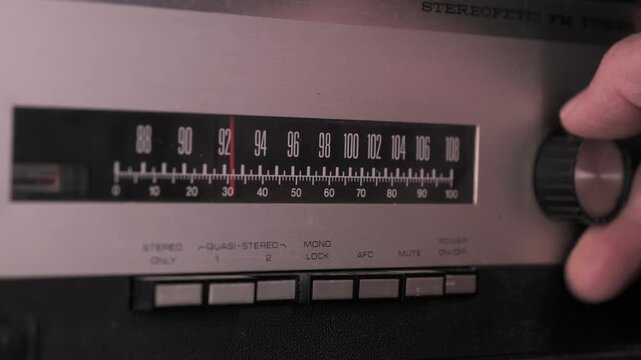 Person searching radio station frequency on vintage fm tuner. Side View