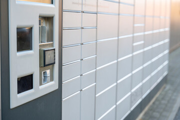 Parcel locker station with service terminal in foreground and rows of lockers behind © molenira