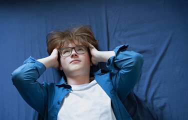 Teenage boy (zoomer) lying down in stress, burnout and mental exhaustion.