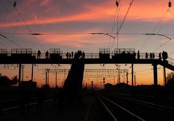 Fototapeta premium This photograph captures a dramatic urban moment at dusk, where human presence, infrastructure, and sky meet in a striking balance