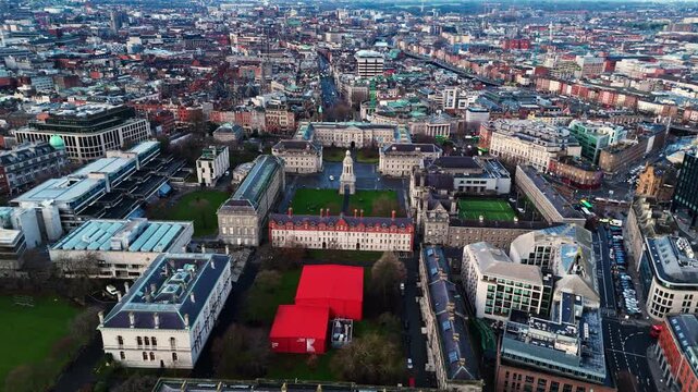 aerial drone shot capturing the trinity college university campus in the heart od the Irish capital of Dublin at sunrise with students and tourists alike wandering about with fields and trees around