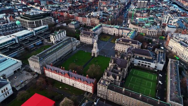 aerial drone shot capturing the trinity college university campus in the heart od the Irish capital of Dublin at sunrise with students and tourists alike wandering about with fields and trees around