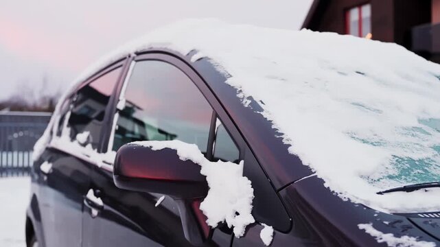 Snow-covered parked car with frozen windshield wipers and side mirror clumped with slush. Cold winter morning vehicle cleaning and driving safety concept.