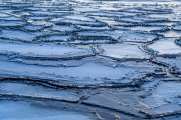 Fototapeta premium Frozen lake surface with cracked ice patterns