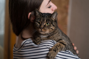 Close-up of a young сaucasian woman hugging a cute, friendly, fluffy domestic cat. Pet, animal.