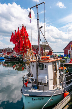 BOLTENHAGEN, DEUTSCHLAND &ndash; 06.06.2022: Fischkutter im Hafen von BOLTENHAGEN vor roten Fischerh&auml;usern und Fangzubeh&ouml;r