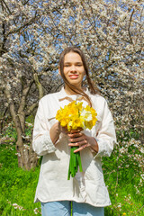 Young woman holding a bouquet of daffodils in her hands