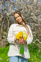 Young woman holding a bouquet of daffodils in her hands