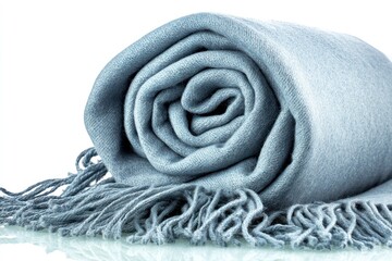 A tightly rolled, soft, light-blue throw blanket with fringe, against a clean white background