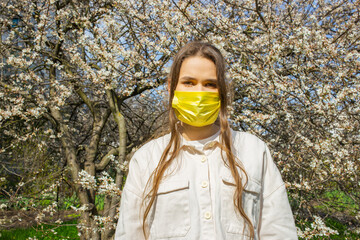 Young woman wearing protective face mask standing outdoors during pandemic