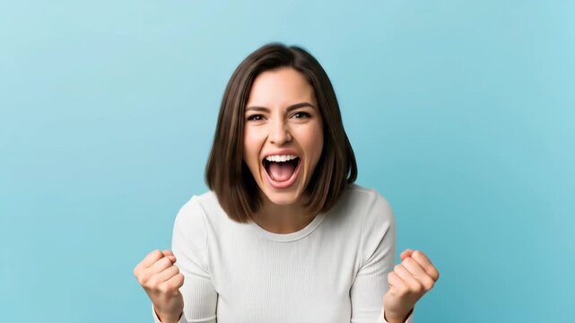 Young caucasian woman expressing excitement with cheering and fist-pumping motion on a blue background