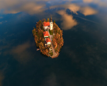 Aerial view of an island sanctuary, where a church spire pierces the sky amidst the lake's embrace, Spodnja Lua, kofja Loka, Slovenia.