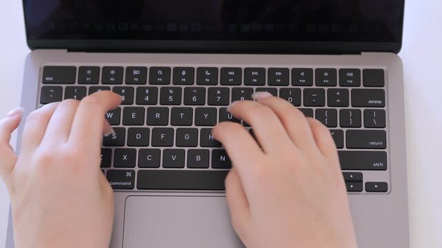 Person is typing on a laptop keyboard. The keyboard has a number pad and a shift key