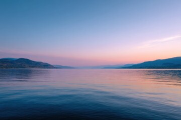 Fototapeta premium Serene lakeside sunrise with calm waters and mountain silhouette