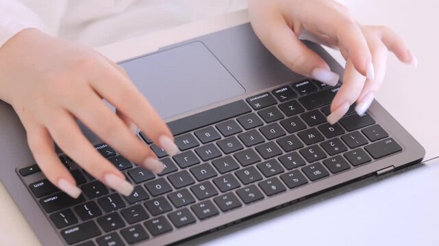 Woman is typing on a laptop keyboard. She is using the number pad and the shift key