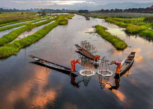 Aerial view of Inle Lake fishermen casting traditional conical shaped nets, their orange robes contrasting against the water, Inle Lake, Inle Lake, Myanmar.