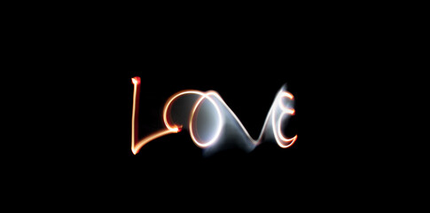 Fototapeta premium Écriture lumineuse du mot LOVE en light painting sur fond noir, concept de romance et de passion