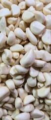 Bulk of peeled garlic cloves background. Fresh white organic garlic for herbal medicine, spicy seasoning, and aromatic cooking ingredient. Healthy produce.