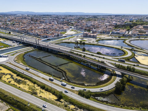 Aerial view of the bustling traffic flowing across bridges and roundabouts, contrasted against the serene waters of Aveiro's canals, Aveiro, Portugal.