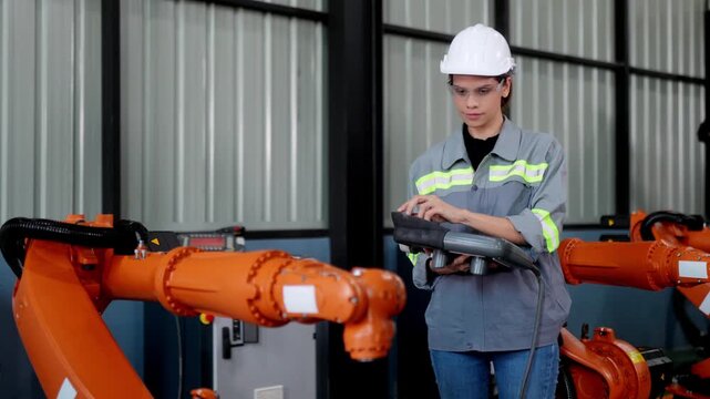 Female Engineer check and control welding robotics automatic arms machine in intelligent factory automotive industrial with monitoring system software. Digital manufacturing operation. Industry 4.0