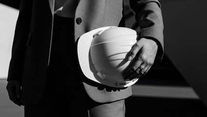 Business professional holding white hard hat in modern office