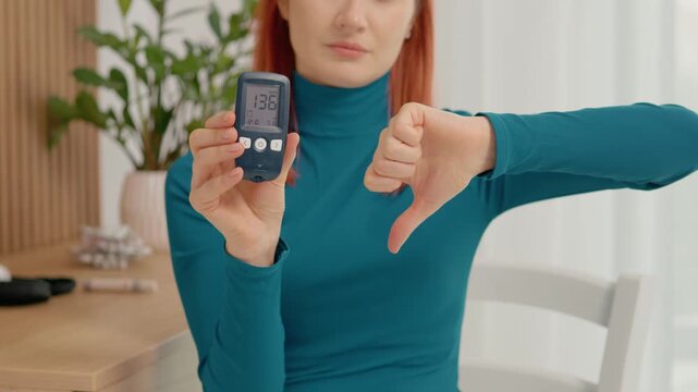 A woman checks her blood sugar level using a glucometer. She shows the camera the reading of 136 mg dL and expresses disappointment with a thumbs down.