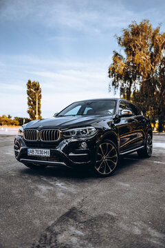 Vinnytsia; Ukraine; July 30, 2020: Black BMW X6 against the background of yellow trees in the parking lot