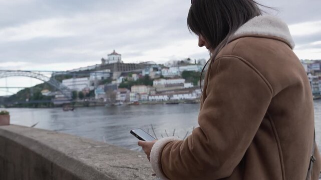 Woman using phone on promenade overlooking dom lu&iacute;s i bridge