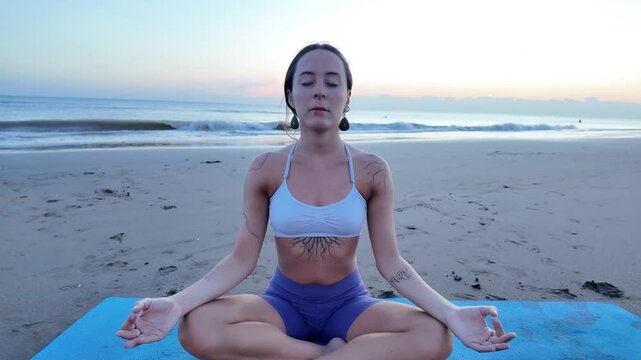 Lesbian woman meditating on a beach at sunrise