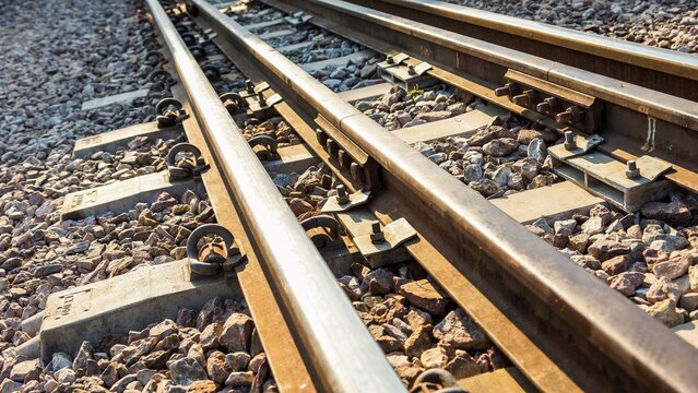 Close-up view of parallel railway tracks with steel rails and gravel ballast, showing linear perspective, transportation infrastructure, and industrial travel concept.