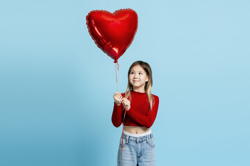 Child looking up at a shiny red heart balloon, symbolizing childhood joy and affection