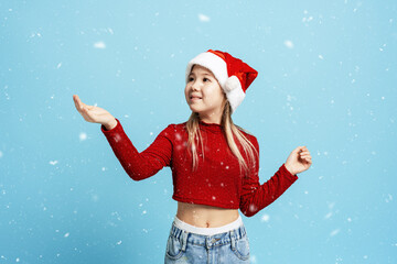 Fototapeta premium Young girl in santa hat feeling joy and excitement during winter holiday snowfall