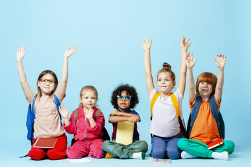Diverse school children raising hands, actively learning and participating in class