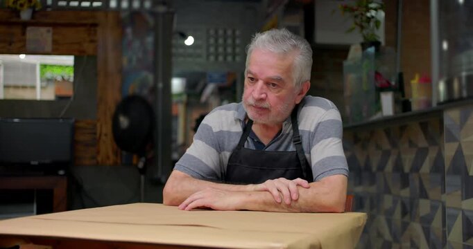 Concerned small business owner sits alone at table showing despair uncertainty and emotional weight of struggling to sustain neighborhood caf&eacute; during hard economic times