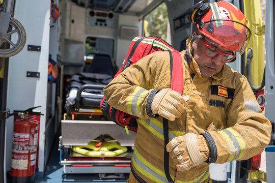 Firefighter wearing protective gear putting backpack in fire engine