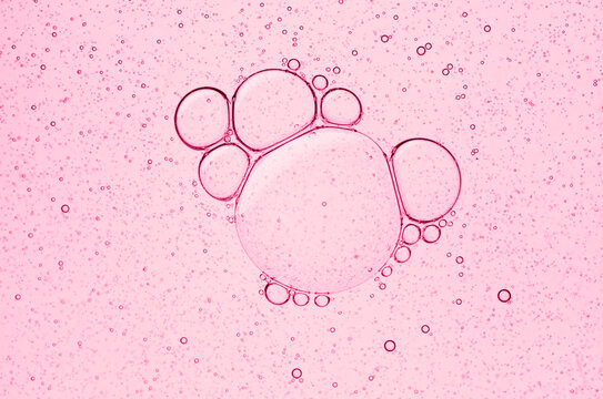 Abstract pink liquid texture with bubbles. Beauty product sample swatch of facial oil, serum or gel toner. Macro photography of cosmetic emulsion
