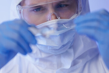 Caucasian male scientist in protective gear analyzing sample in laboratory