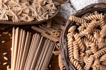 primo piano di diversi tipi di pasta su uno sfondo di legno © zole4