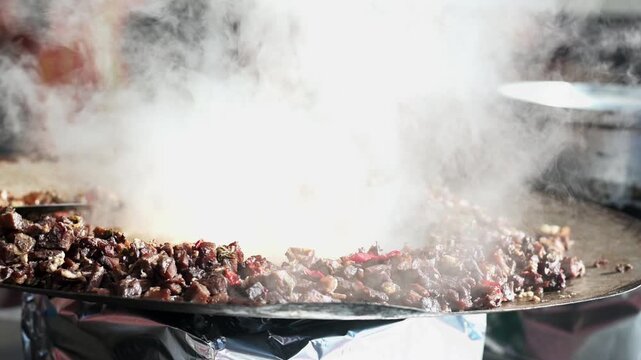 Authentic close-up video of Turkish sa&ccedil; kavurma meat cooking in a pan. Meat pieces boiling with oil and sauce, producing steam during the natural cooking process. Real culinary preparation, traditiona