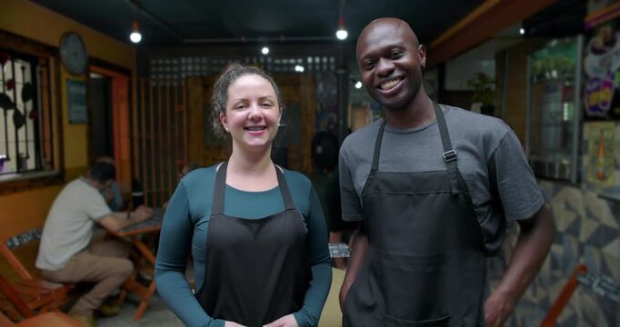 Happy small business caf&eacute; staff standing together inside neighborhood restaurant expressing optimism cooperation pride shared achievement service identity community belonging