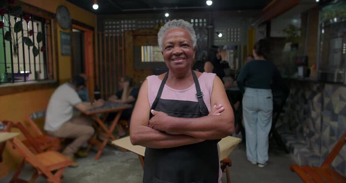 Confident elderly African American caf&eacute; staff member standing inside neighborhood restaurant expressing experience resilience dignity leadership presence pride small business work