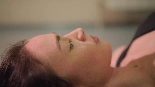 white woman practicing controlled breathing, focused face and steady gaze, preparing for strength sets with mental visualization, minimal movement, studio glow, trainer guidance implied, calm