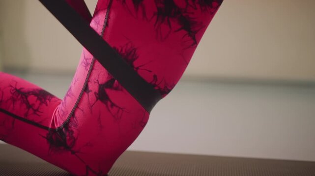 closeup dancer foot on yoga mat pink tiedye leggings with black resistance band performing controlled plantar flexion in soft studio light focusing technique warmup precision ankle strength