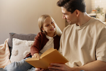 Father and daughter bonding with their golden retriever at home