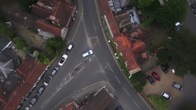 Aerial view of a residential street intersection with parked cars and homes.